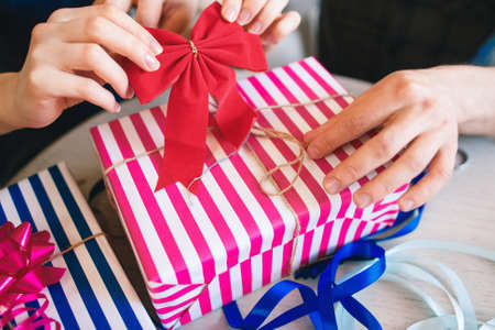 Pink box decorating with red bow, close-up. Christmas gifts wrapping. Surprise, love, friendship, joy conceptの写真素材