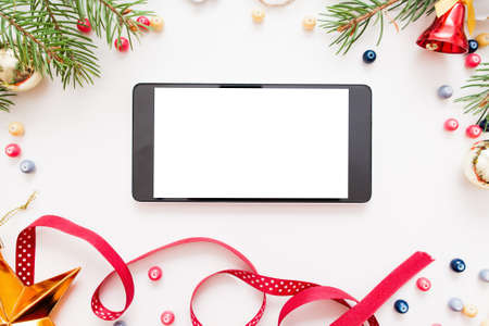 Smartphone with blank screen in Christmas frame, mockup. New year trumpery and empty smartphone on white background, copy space for text or advertisement, voidの写真素材
