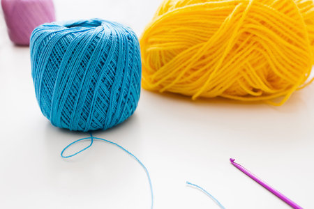 Bright colorful balls of yarn and crochet. Knitting equipment on white background, free space for...