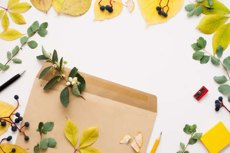 Brown envelope in autumn leaves frame, copy space. Vintage paper cover with green and yellow leaves on white background. Fall inspiration, creativity conceptの写真素材