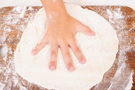Kid making handprint on raw dough closeup. Child hand playing with pastry on kitchen. Homemade cuisine, culinary, happy childhood conceptの写真素材