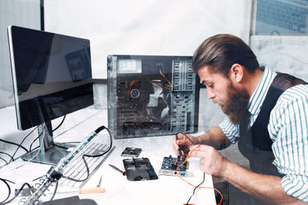 Repairman soldering circuit, double exposure. Bearded electrician welding electronic component of computer unitの写真素材