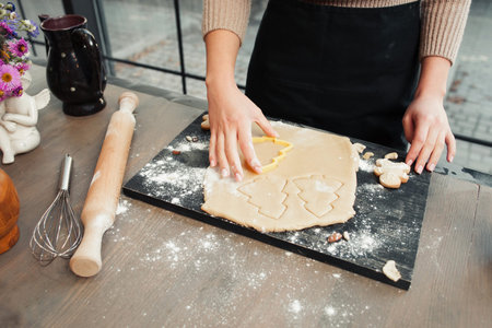 Christmas tree gingerbread cookies making. Female hands forming traditional Christmas treat at kitchen. Homemade bakery, xmas sweet, winter holidays conceptの写真素材