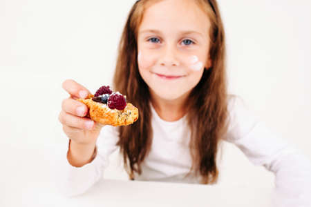 Girl treating you with berry cake, free space. Little smiling lassie propose sweet cookie to camera. Homemade bakery, children culinary, pastry making conceptの写真素材