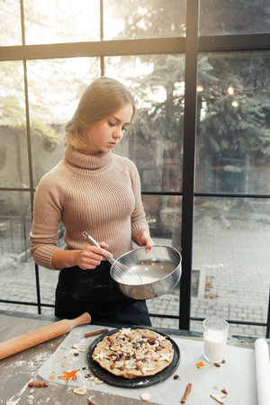 Woman preparing dough for pie. Young cooker making homemade bakery with dried fruits. Culinary...
