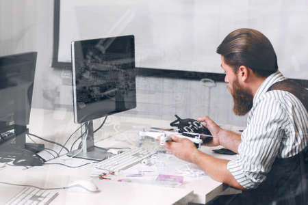Drone remote control tuning, double exposure. Engineer checking connection between quadrocopter and rc transmitter at officeの写真素材