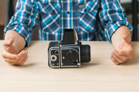 Professional retro photo camera presentation. Unrecognizable photographer talking about old fashioned photographing equipment, free space for text or advertisementの写真素材