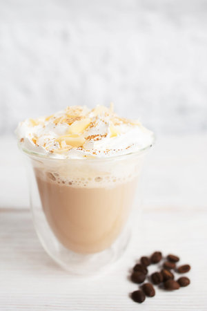 Close-up of cappuccino cup with coffee beans on white background. Tasty appetizing creamy latte in glass mug. Dessert, restaurant serving, hot beverage conceptの写真素材