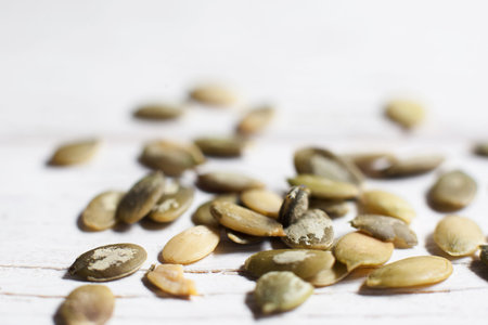 Pumpkin seeds on white background close-up. Texture of squash semen, agricultural backdropの写真素材
