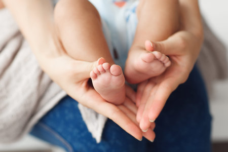 Newborn baby legs in mother hands, close-up. Mom holding her little kid feet. Happy family, new life conceptの写真素材