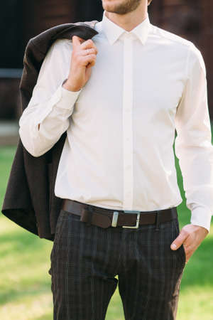 Man in suit with relaxed attitude, one hand in pocket, other hand holding jacket over his shoulder. Close-up of unrecognizable businessman rest after hard dayの写真素材