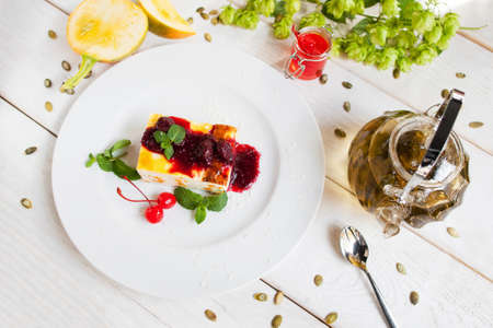 Cheesecake with red topping and tea. Top view on table with dessert and pot with beverage. Confectionery, seasonal menu, healthy food conceptの写真素材