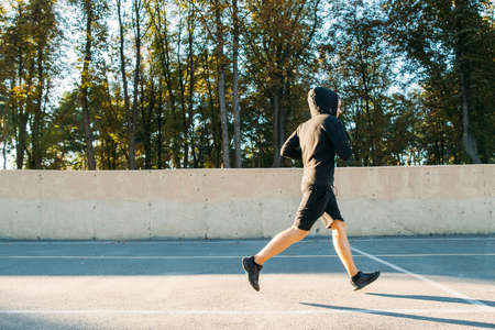 Finish of intensive workout of professional runner. Fit sporty man is at outdoor stadium. Fitness, training, healthy lifestyle conceptの写真素材