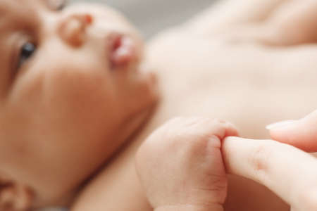 Little baby holding mothers finger close-up. Innocence, security, purity, motherhood, new life, love and happiness concept.の写真素材
