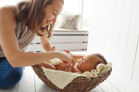 Smiling mother playing with newborn baby, profile. Laughing woman touching nose of her little child. Happy family, love, innocence, motherhood conceptの写真素材