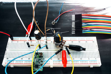 Development of new technological device. Top view on inventor table with breadboard with different connections and set of colorful cablesの写真素材