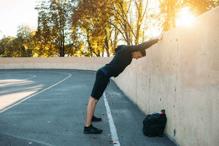 Sportsman making warming-up exercises. Male athlete training on open-air stadium, free spaceの写真素材