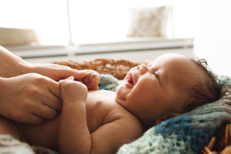 Baby smiling at mother, close-up. Adorable newborn child looking up at mother and holding her hands. Love, innocence, cuteness conceptの写真素材