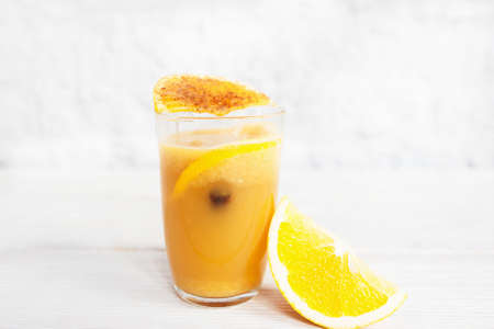 Fresh orange juice in glass on white background. Portion of citrus fresh with orange slice and spices, free space for text. Refreshment, cocktail, vitamins conceptの写真素材