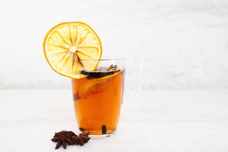Cup of tea with orange and cinnamon on white background, free space. Glass of hot spiced winter drink with anise stars, free space for textの写真素材