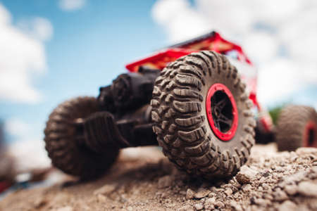 Red crawler wheels outside close-up. Rc car standing on rock, blue sky with clouds on backgroundの写真素材