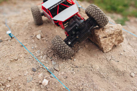Top view on rc car overcoming rock block on track. Crawler racing on rally trace. Toy truck on landscape road, free space for textの写真素材