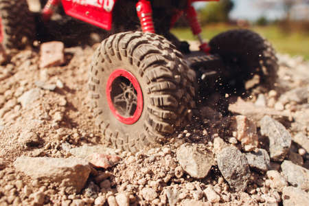 Close-up of wheel slipping in rock trace. Toy truck skid on rocky surface, hard road condition, traffic trouble conceptの写真素材