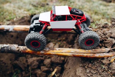 Rc car roading on wooden beams above hollow. Toy suv riding on log handmade bridge over yawner with mud. The competition of radio-controlled toysの写真素材