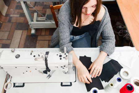 Seamstress working at sewing machine top view. Young female tailor working at her workplace. Tailoring process, designer workshop, garment industry conceptの写真素材