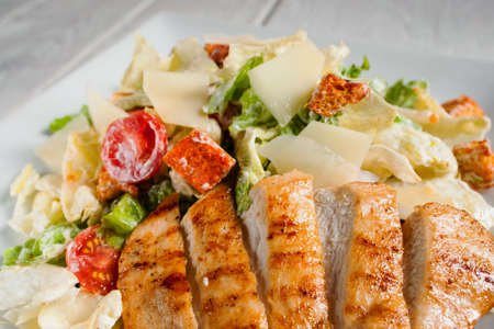 Fried chicken strips with fresh vegetable salad close-up. Served caesar on white plate. Mediterranean cuisine, restaurant menu, appetizing conceptの写真素材