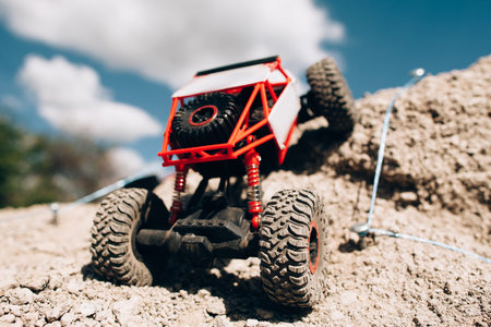 Rc car overcoming rock hill close-up. Crawler rising on rough surface of rocky rally track....