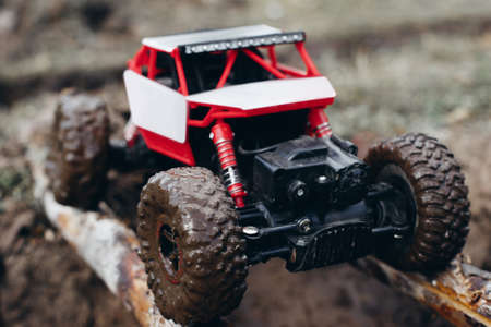 Toy car roading on wooden beams through mud. Crawler testing on hard weather conditions. Industry, hobby, entertainment ,bad weather, competition of controlled toys outdoor, survival conceptの写真素材