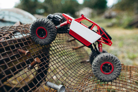 Toy truck overcoming grille with screws profile. Side view on rc crawler riding on metal lattice,...