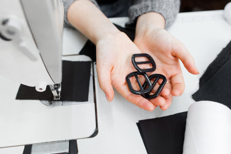 Designer hands with black buckles top view. Female tailor hands holding findings. Garment industry,...