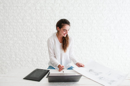 Smiling woman at workplace, free space. Glad designer retouching sketch on laptop. Happy artist...