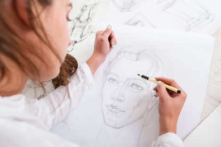 Artist drawing pencil portrait close-up. Woman painter creating picture of woman on big whatman. Art, talent, craft, hobby, occupation conceptの写真素材