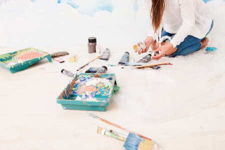 Artist sitting on floor with tools, free space. Top view on unrecognizable painter, working on ground with dye, brushes and palette, copy space, white background. Art, craft conceptの写真素材