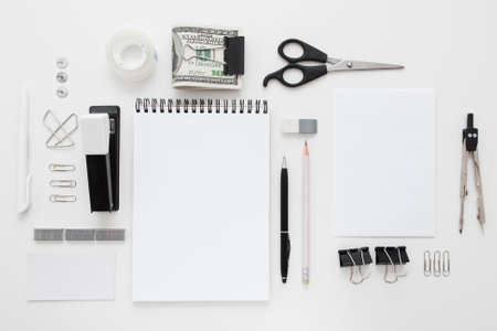 Set of black and white office supplies flat lay. Top view on various stationery on desk: notepads, pencils, scissors, stapler, clip, pins, pen, pencil and bundle of money. Business accessories mocupの写真素材