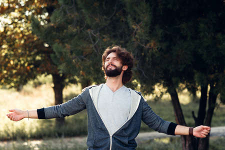 Young smiling man enjoying environment, free space. Happy bearded guy trying to hug whole world. Happiness, pleasure, relax, joy, fun, life love conceptの写真素材