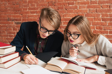 Pair of students carefully reading textbook. Young man explain girl hard material in book....