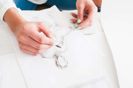 Female fashion designer sketching at workshop. Close-up of artist hands drawing rough draft with pencils. Art, craft, talent, inspiration, creativity conceptの写真素材