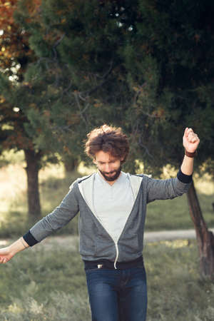 Stylish man dancing in park, free space. Young stylish smiling guy fooling outdoor. Fun, joy, rest, good mood, pleasure, active lifestyle conceptの写真素材