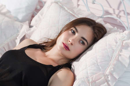 Young woman cant got sleeping in bed closeup. Beautiful lady lying on pillow with opened eyes, thinking about something. Insomnia, worry, fear conceptの写真素材