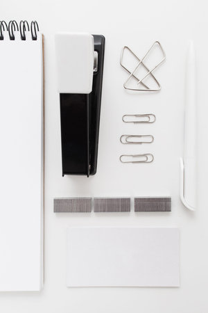Black stapler with clips and stickers flat lay. Top view on black and white office supplies, free...