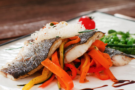 Grilled fish fillet with carrot close-up. Roasted pangasius served on bed of vegetables. Mediterranean cuisine, seafood, restaurant menu conceptの写真素材