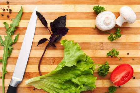 Cutting board with knife and vegetables flat lay. Top view on wooden kitchen workplace with fresh natural ingredients for cooking. Vegetarian cuisine, hobby, food preparation conceptの写真素材