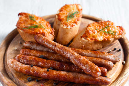Catering platter with grilled sausages and canapes. Set of roasted fat snacks for beer on wooden board. Junk food, dieting, restaurant menu conceptの写真素材