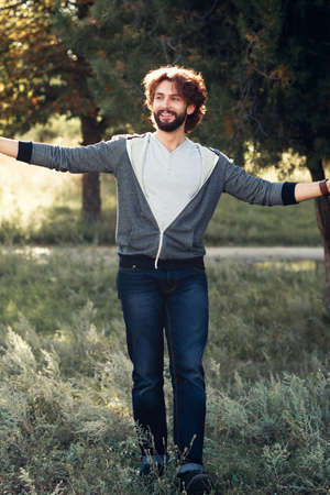 Happy man hugging world, full-length photo. Smiling guy in casual clothes standing with widely spaced hands. Life love, joy, pleasure, relax, happiness conceptの写真素材