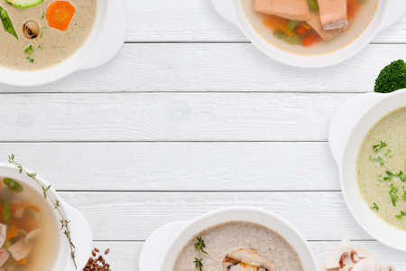 Frame of different soups on white wooden table. Buffet serving of restaurant hot dishes, free space for text. Worldwide cuisine, healthy food, lunch, menu conceptの写真素材
