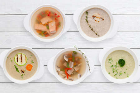Variation of tasty restaurant hot dishes flat lay. Top view on white wooden table with set of different soups. Worldwide cuisine, healthy food, buffet, lunch, menu conceptの写真素材